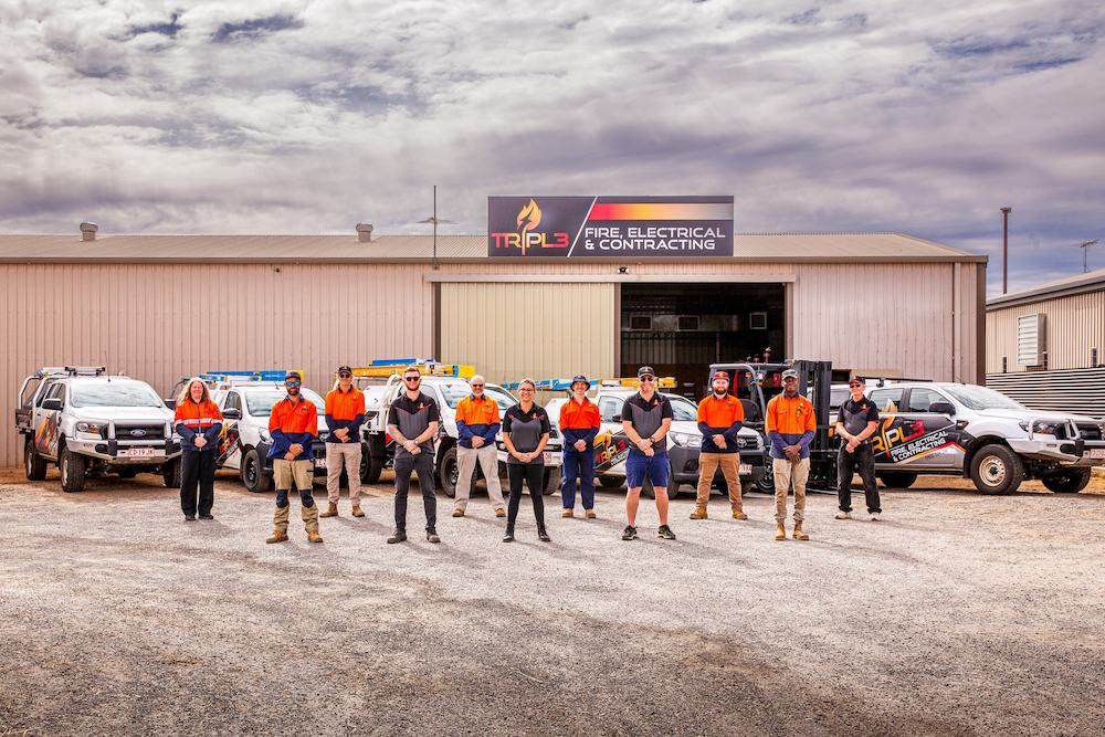 A Group of People Are Posing for a Picture in Front of a Building — Tr!pl3 Fire Electrical & Contracting in Alice Springs, NT