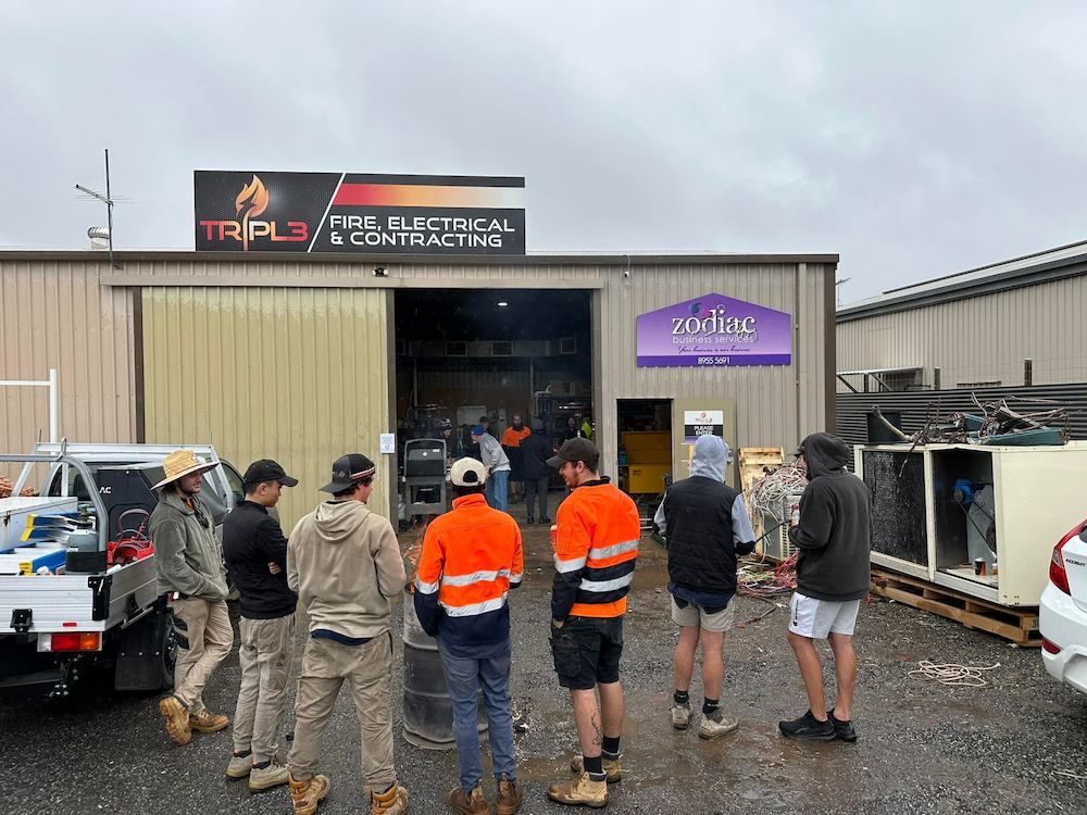 A Group of Men Are Standing in Front of a Building — Tr!pl3 Fire Electrical & Contracting in Alice Springs, NT