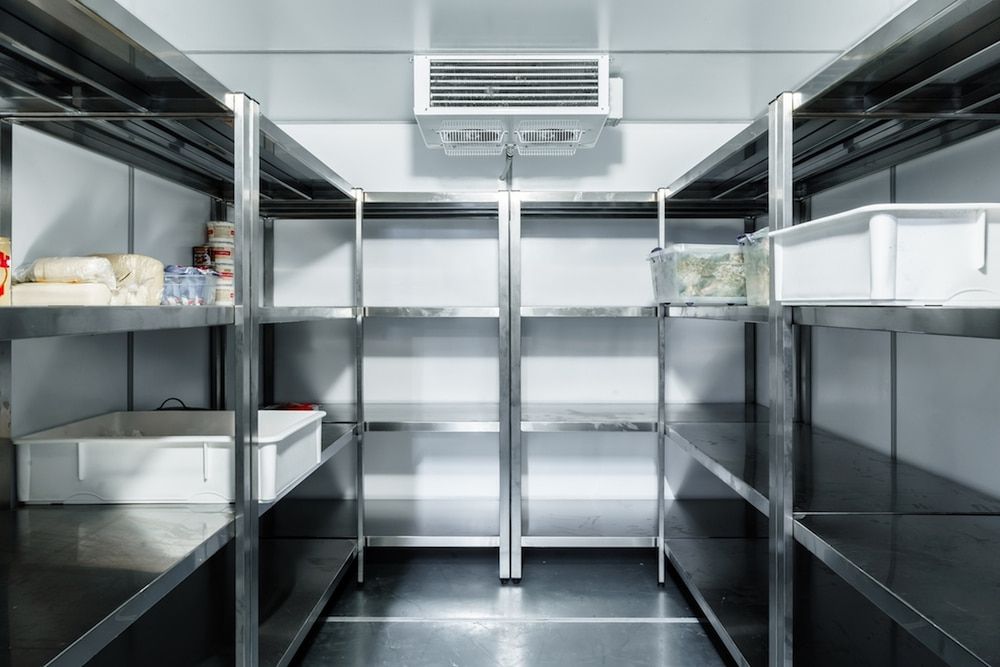 An Empty Refrigerator With Stainless Steel Shelves in a Kitchen — Tr!pl3 Fire Electrical & Contracting in Alice Springs, NT

