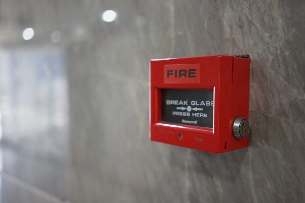 A Red Fire Alarm is Hanging on a Wall — Tr!pl3 Fire Electrical & Contracting in Alice Springs, NT