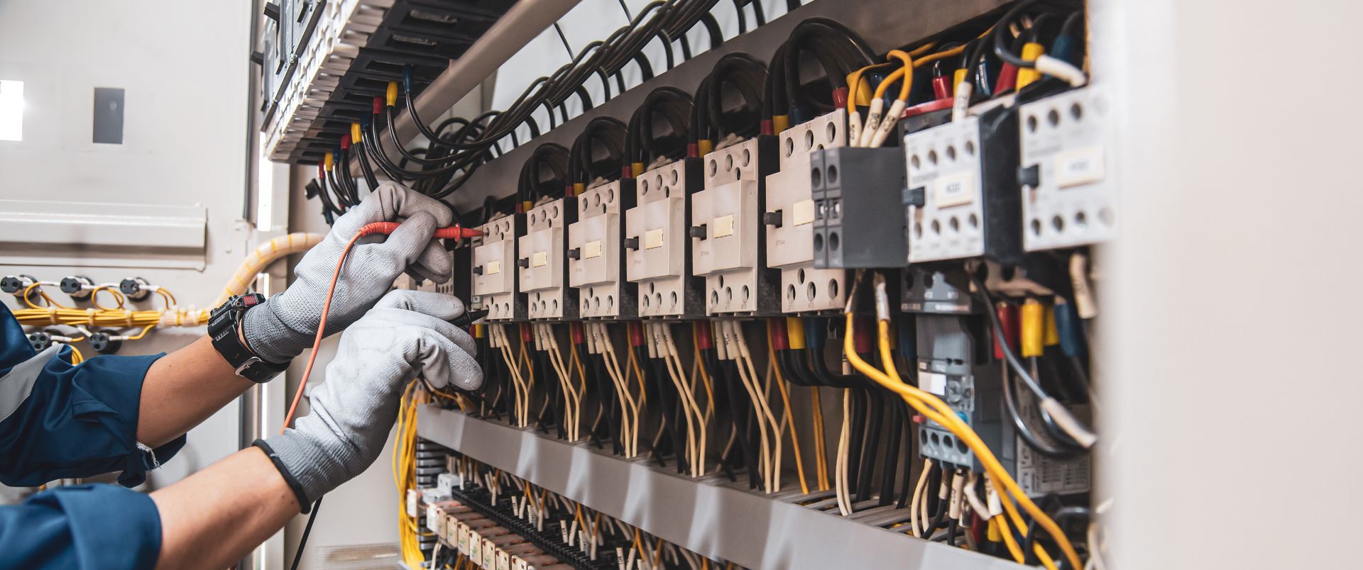 A man is working on an electrical panel with a screwdriver.