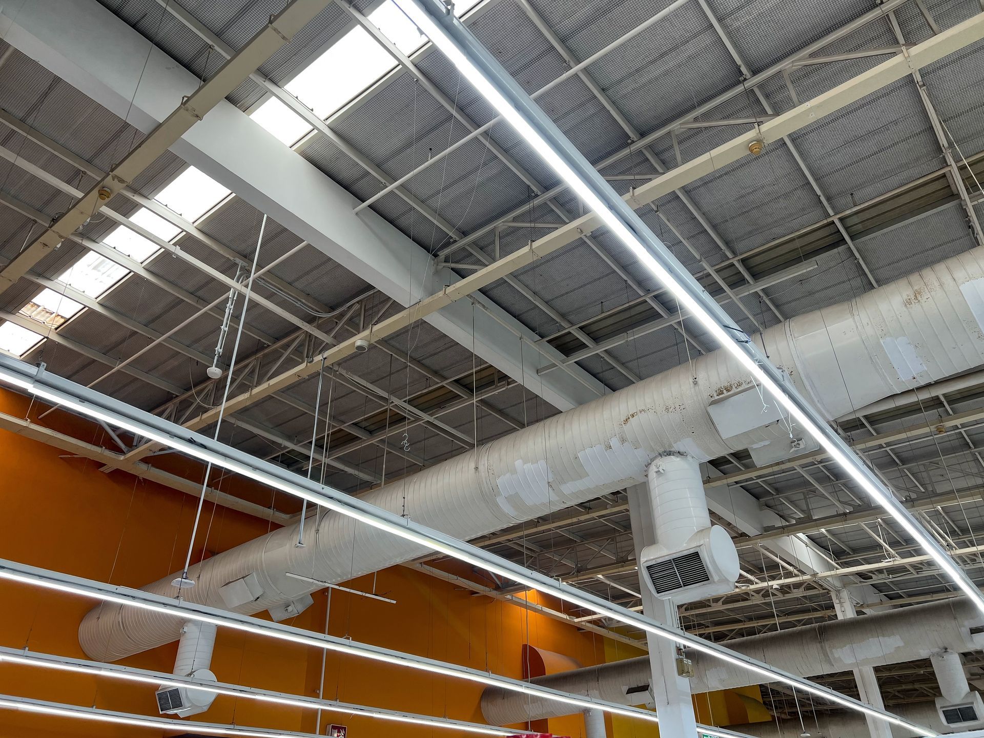 The ceiling of a building with a lot of pipes hanging from it.