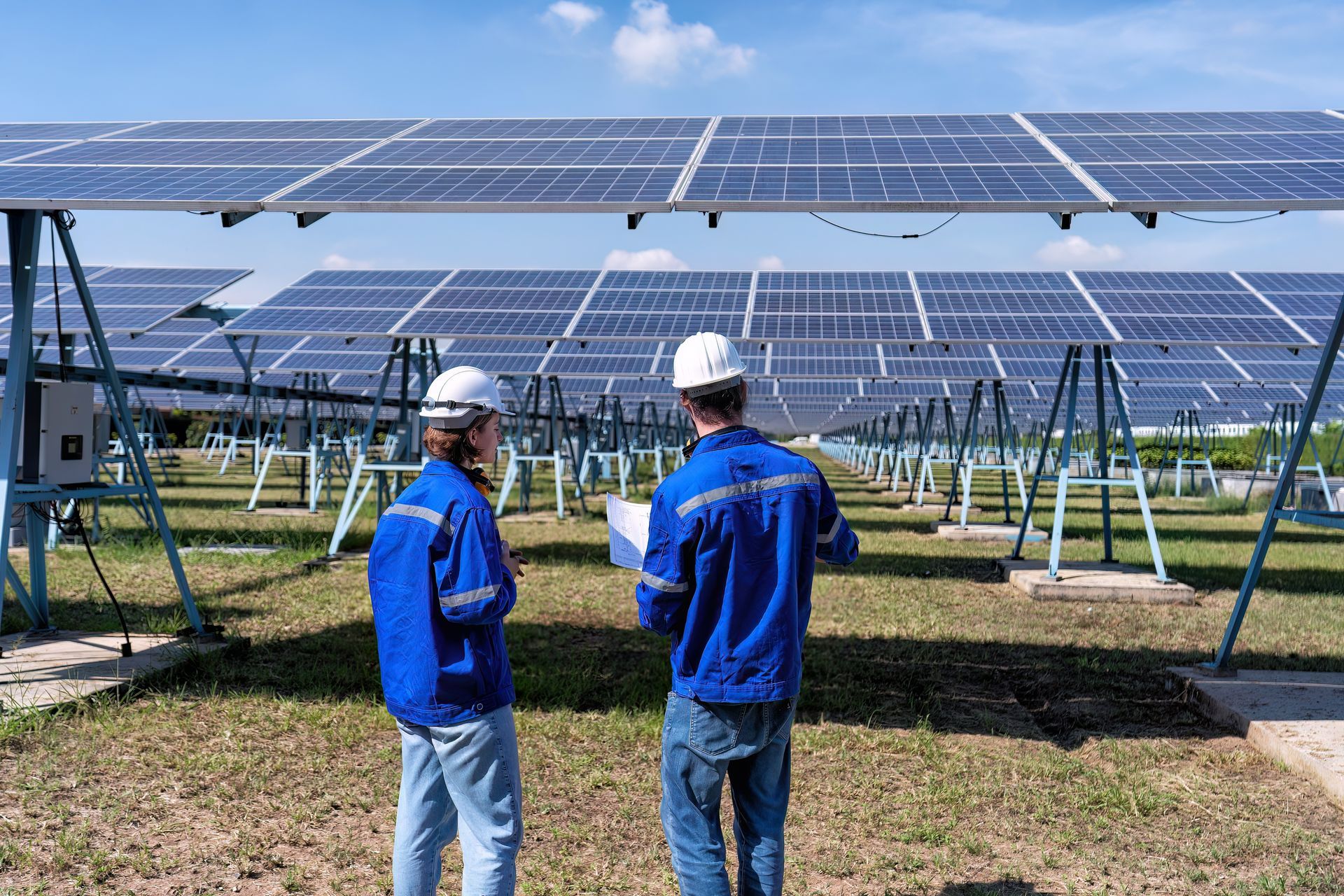 Two men are standing in front of a field of solar panels.