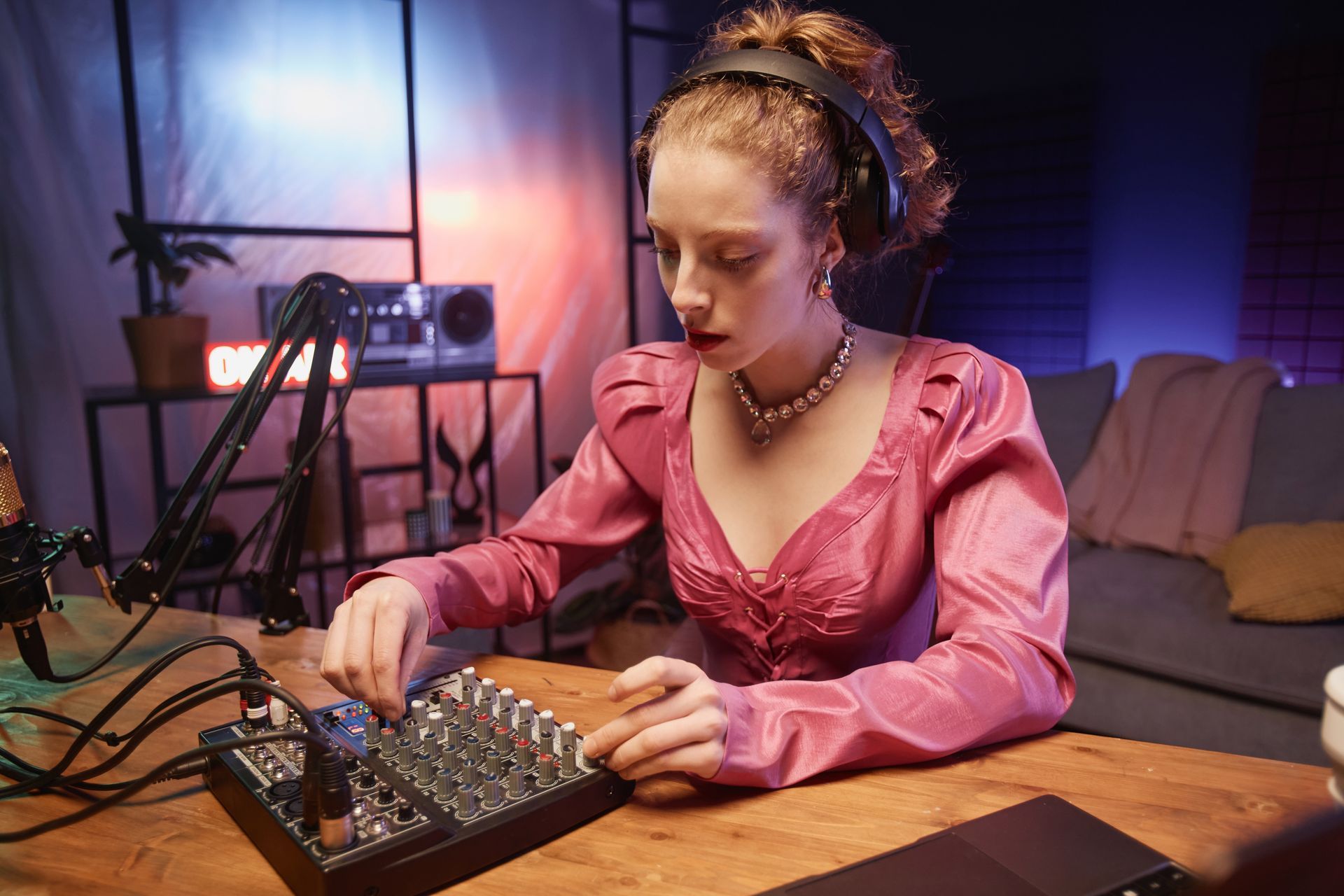 A woman in a pink dress is sitting at a table playing a musical instrument.