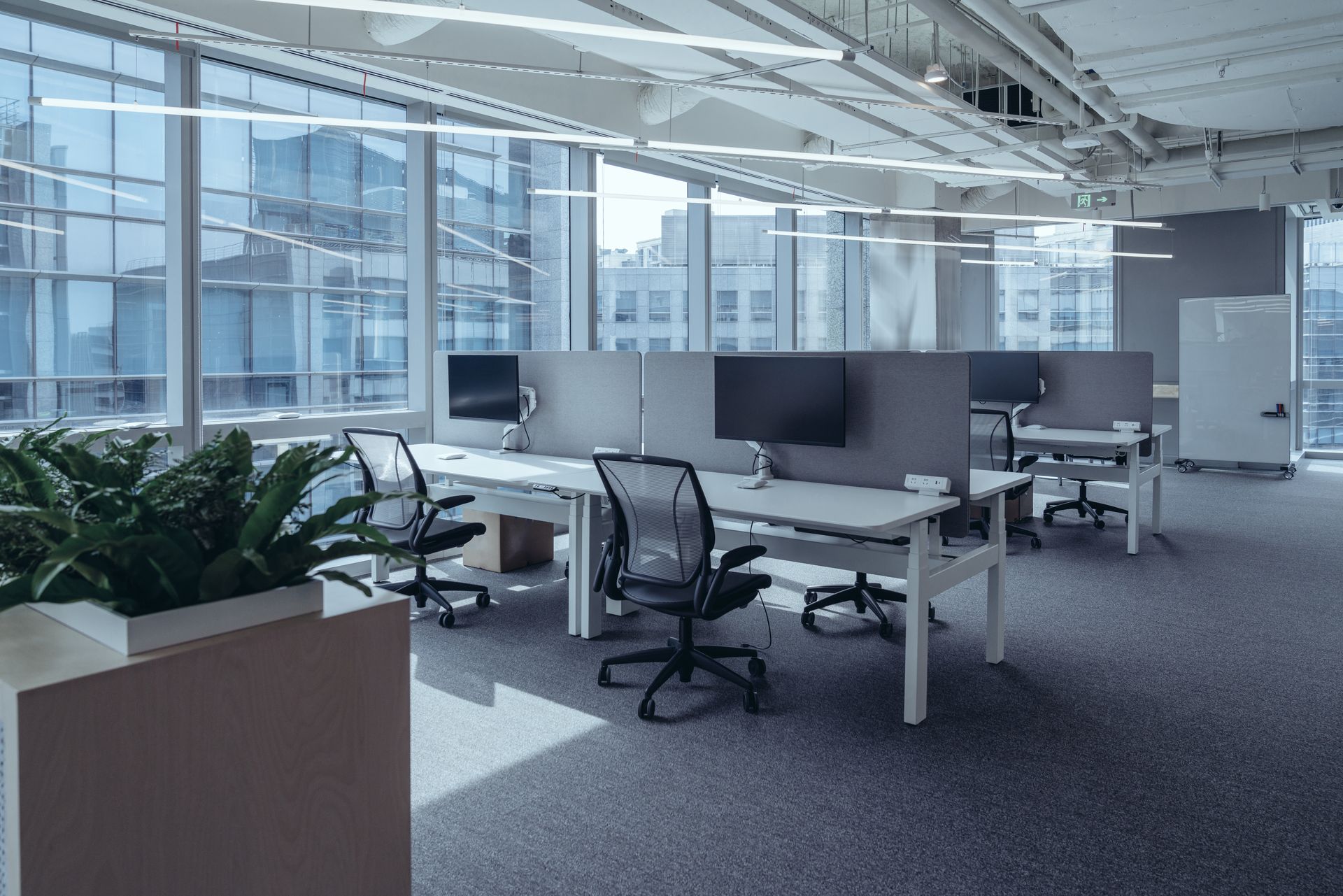 An empty office with a lot of windows and desks and chairs.