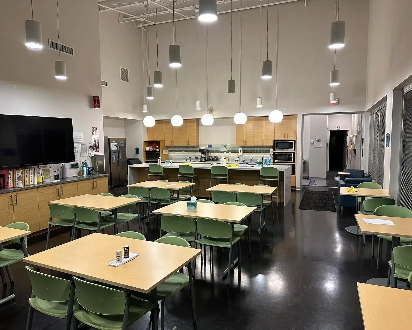 A large commercial dining room with tables and chairs and a kitchen getting janitorial services