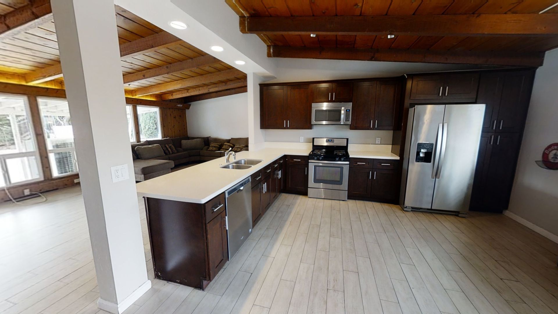 Kitchen with dark brown cabinets, stainless steel appliances, and light wood floors.