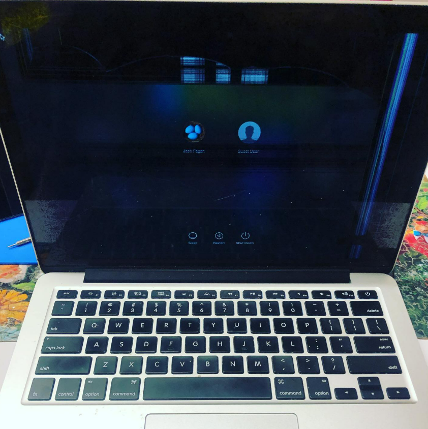 Laptop showing a dark login screen with user icons and a blue vertical light on the right edge