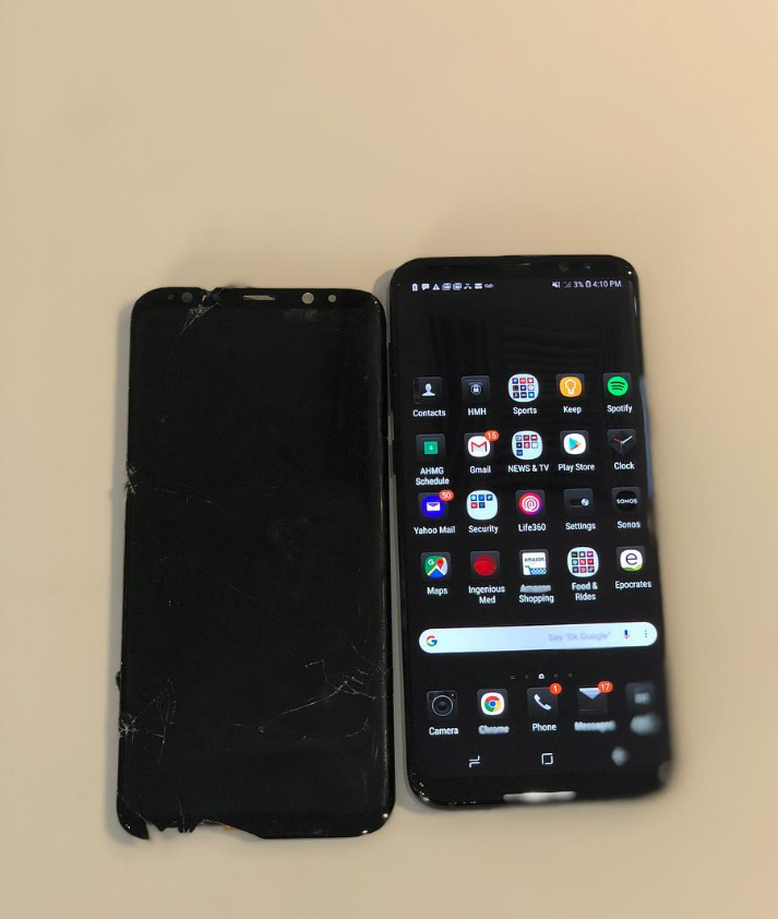 Two smartphones on a beige surface, one black and off, the other on with app icons visible.