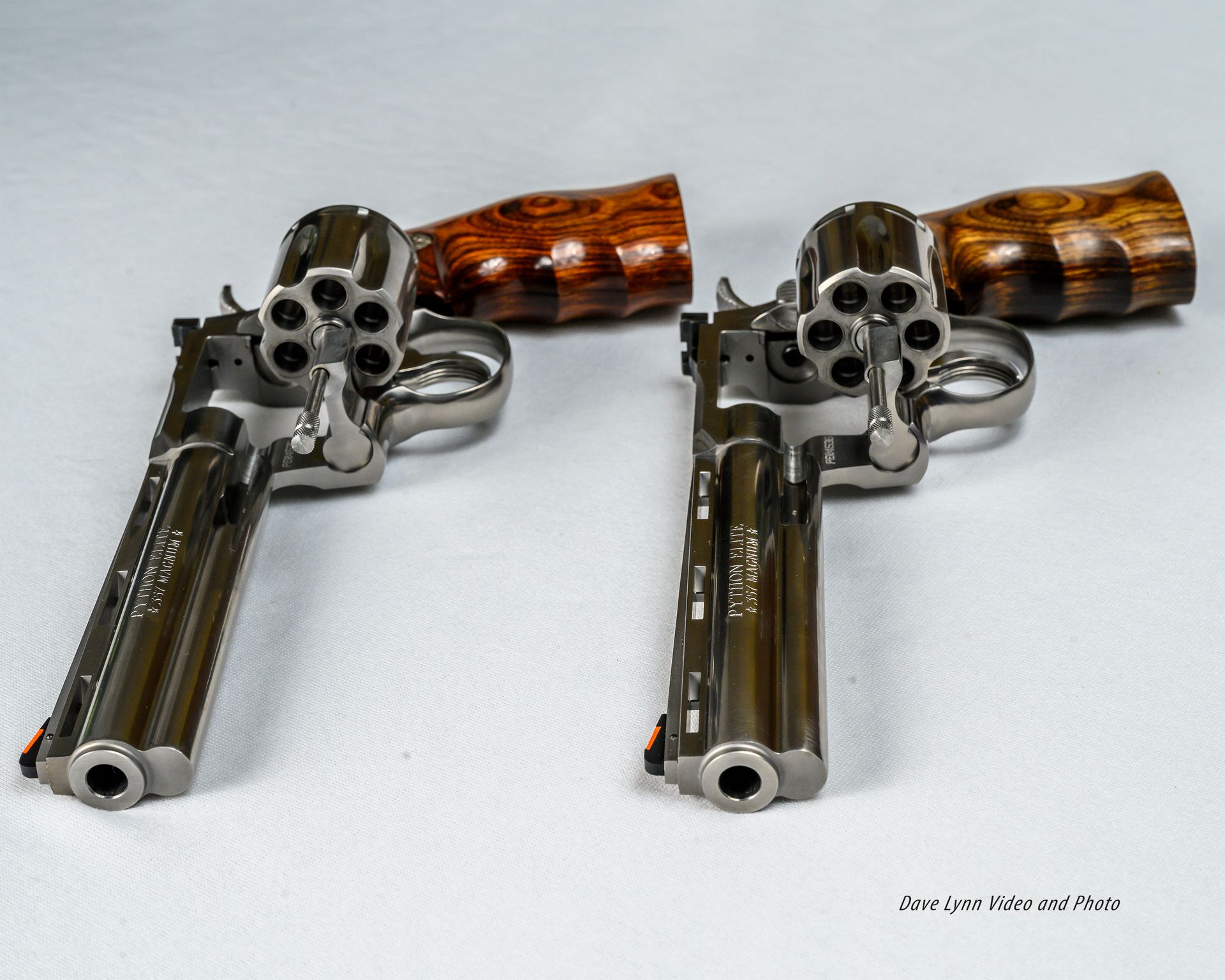 Two silver revolvers with wooden grips on a white background