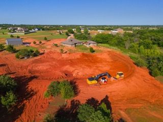 Orange dirt construction site with excavators in a rural landscape