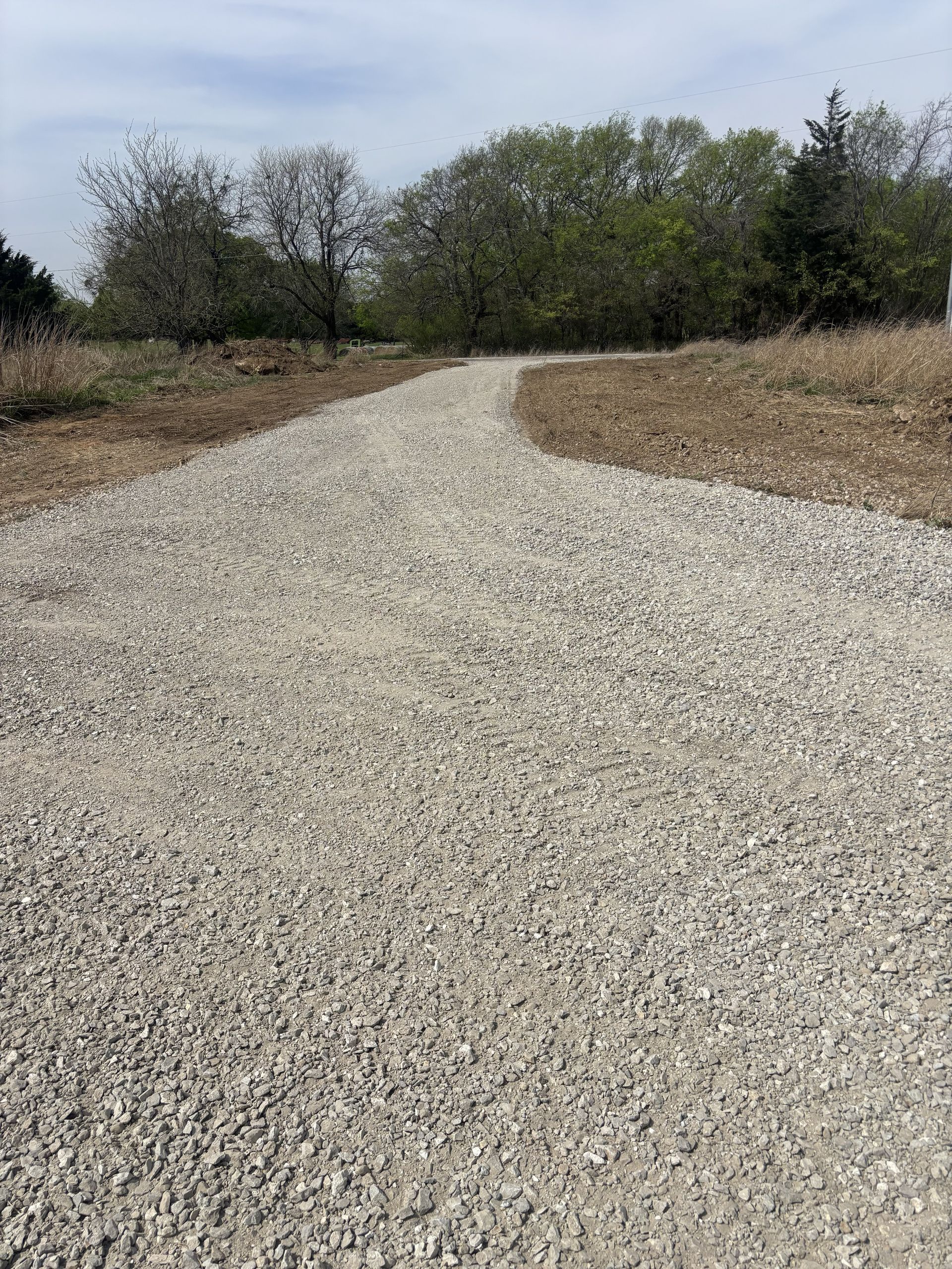 Gravel path curving through dry grass and shrubs under a bright sky