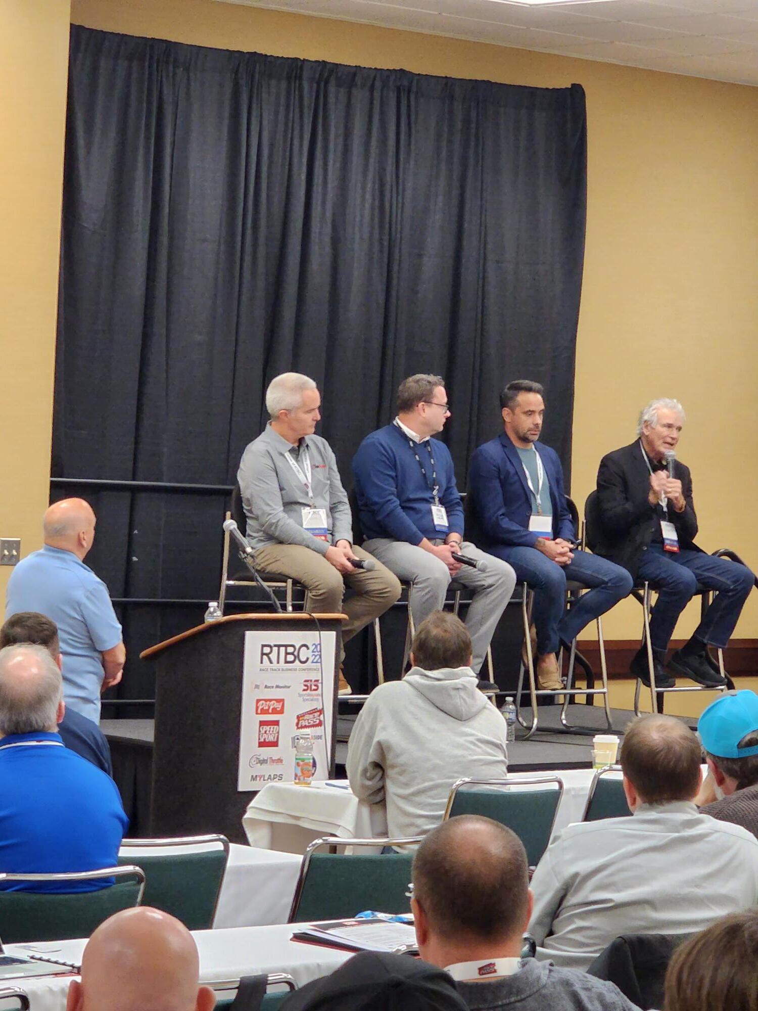 a group of men are sitting on a stage at a conference .