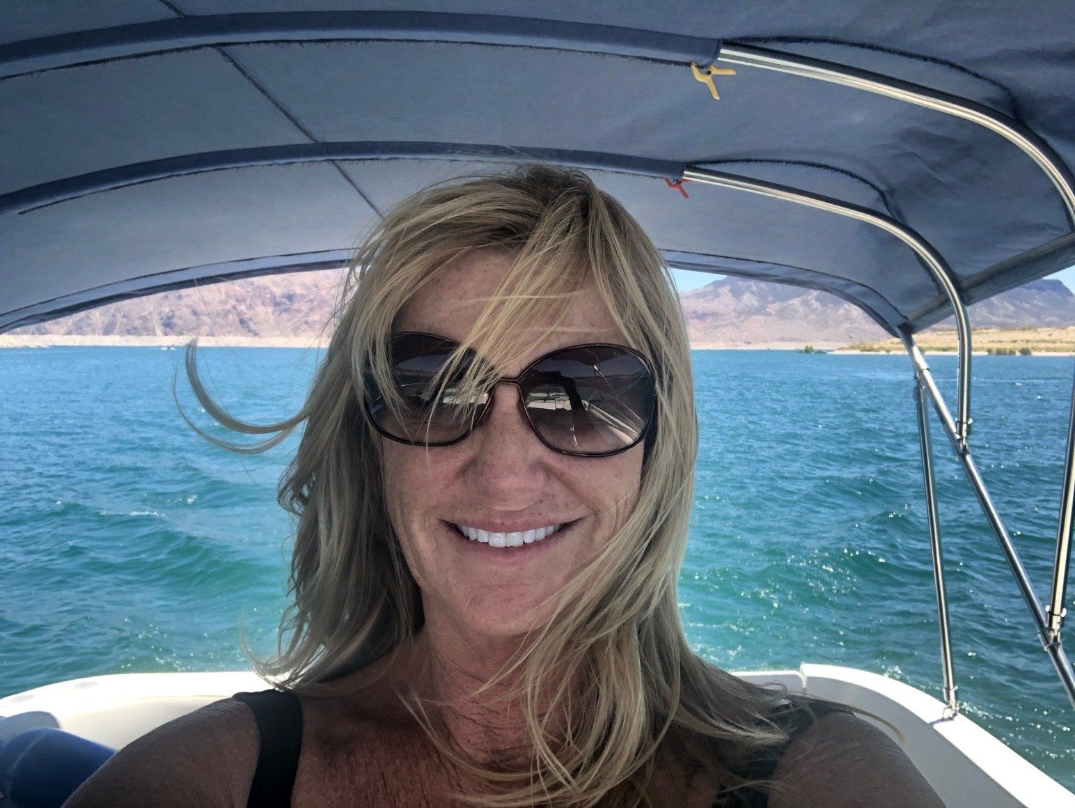 a woman wearing sunglasses is sitting on a boat in the water .