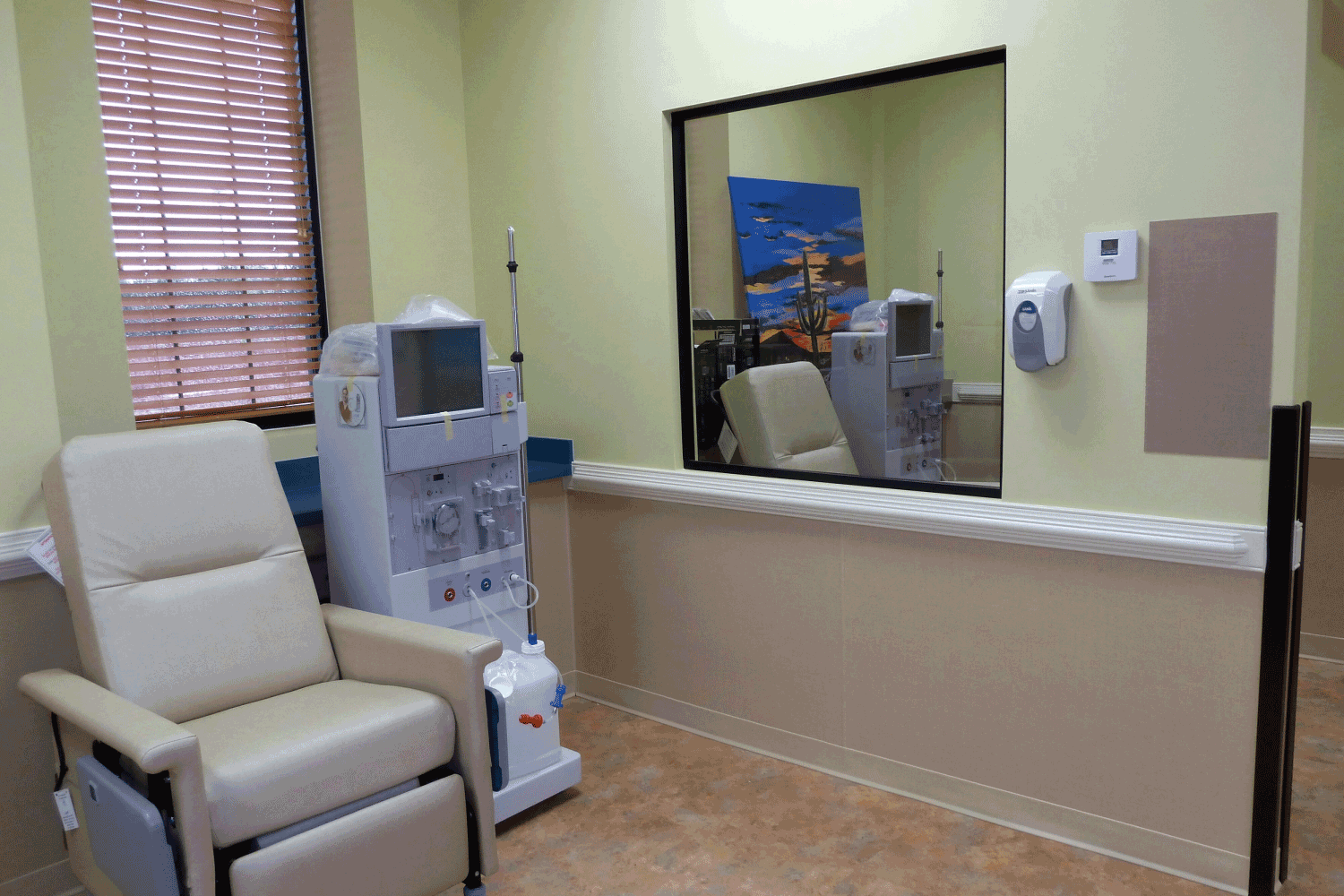 A hospital room with a chair and a dialysis machine