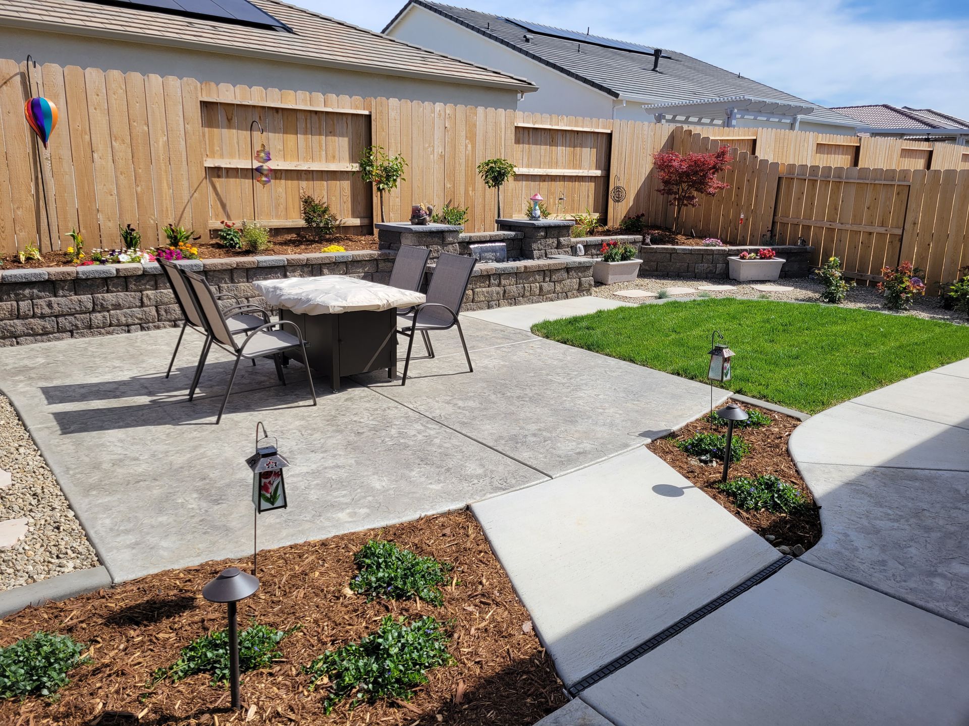 A patio with a table and chairs in the backyard of a house.
