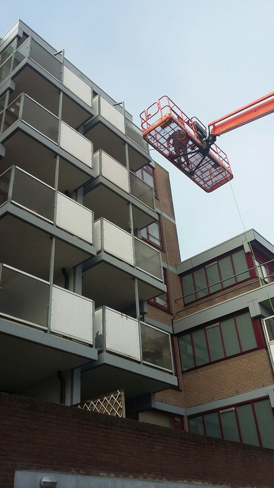 Een groot gebouw met balkons en een kraan ervoor