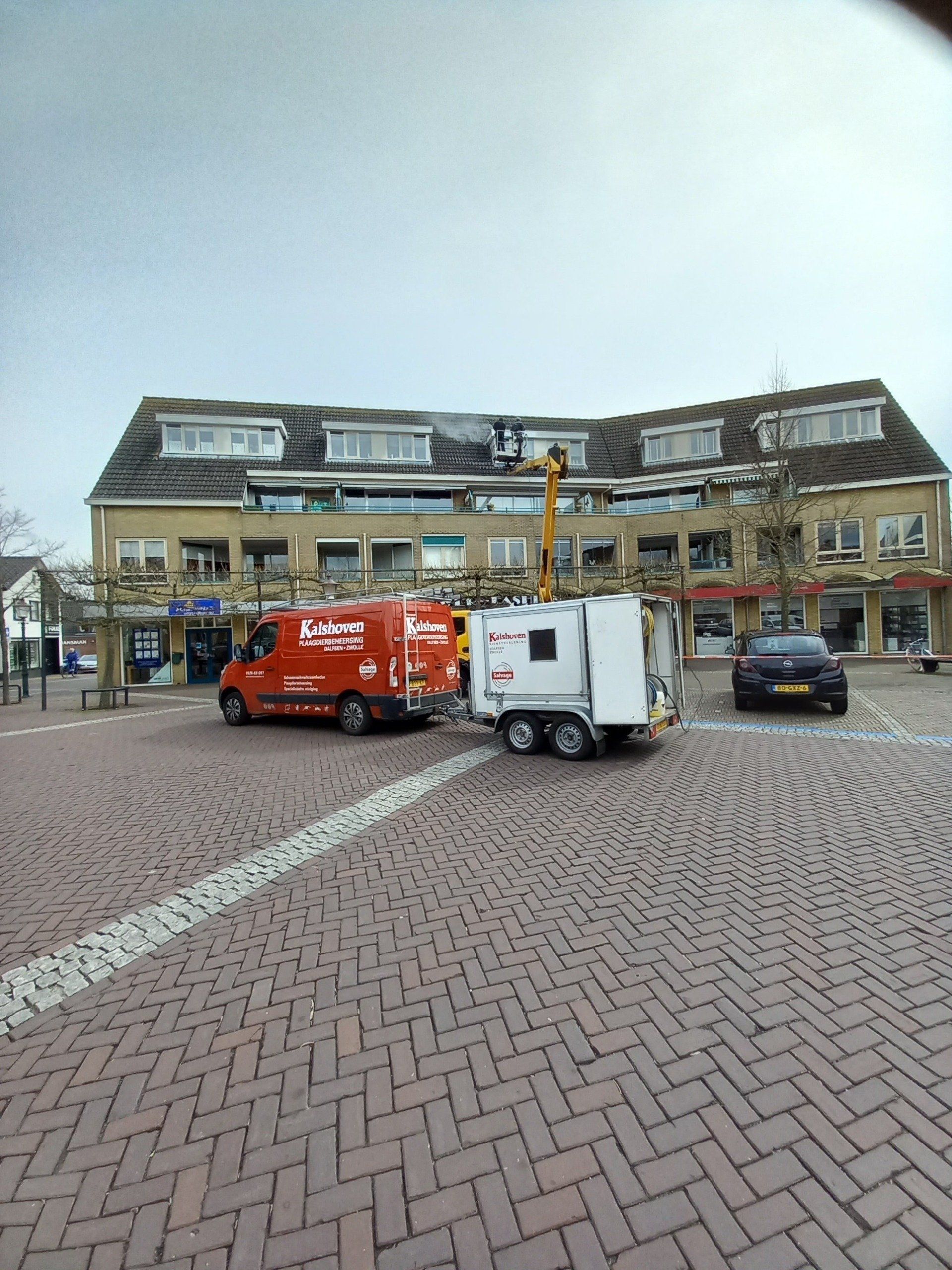 Twee rode busjes staan ​​geparkeerd voor een groot gebouw