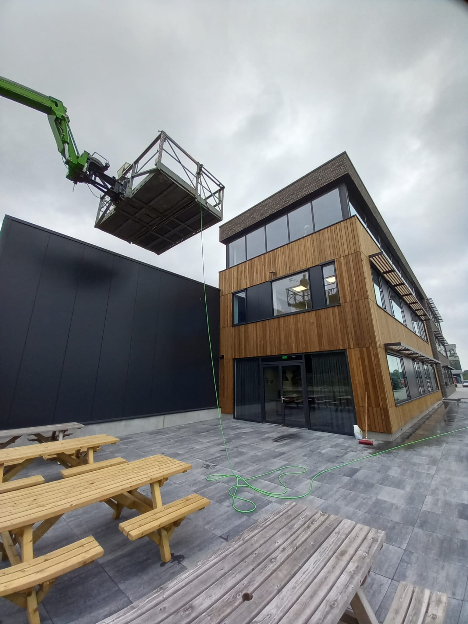 Een groene kraan tilt een houten constructie voor een gebouw.