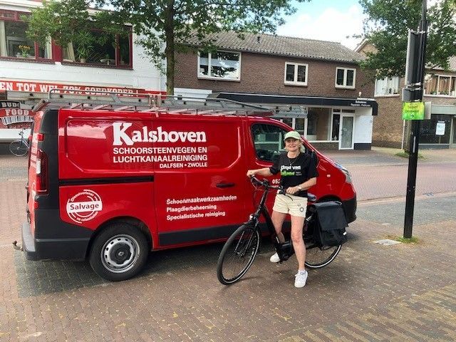 Een vrouw staat naast een rode bestelwagen met het opschrift kalshoven