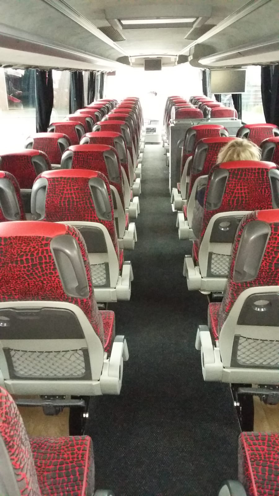 De binnenkant van een bus met rood-witte stoelen