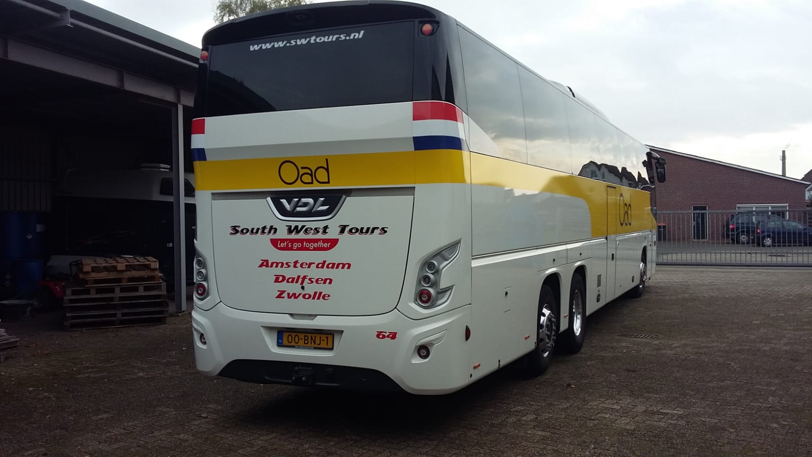 Een witte en gele bus met het woord oad op de achterkant
