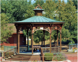 A gazebo with a green roof is surrounded by trees
