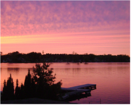 A sunset over a lake with a dock in the foreground