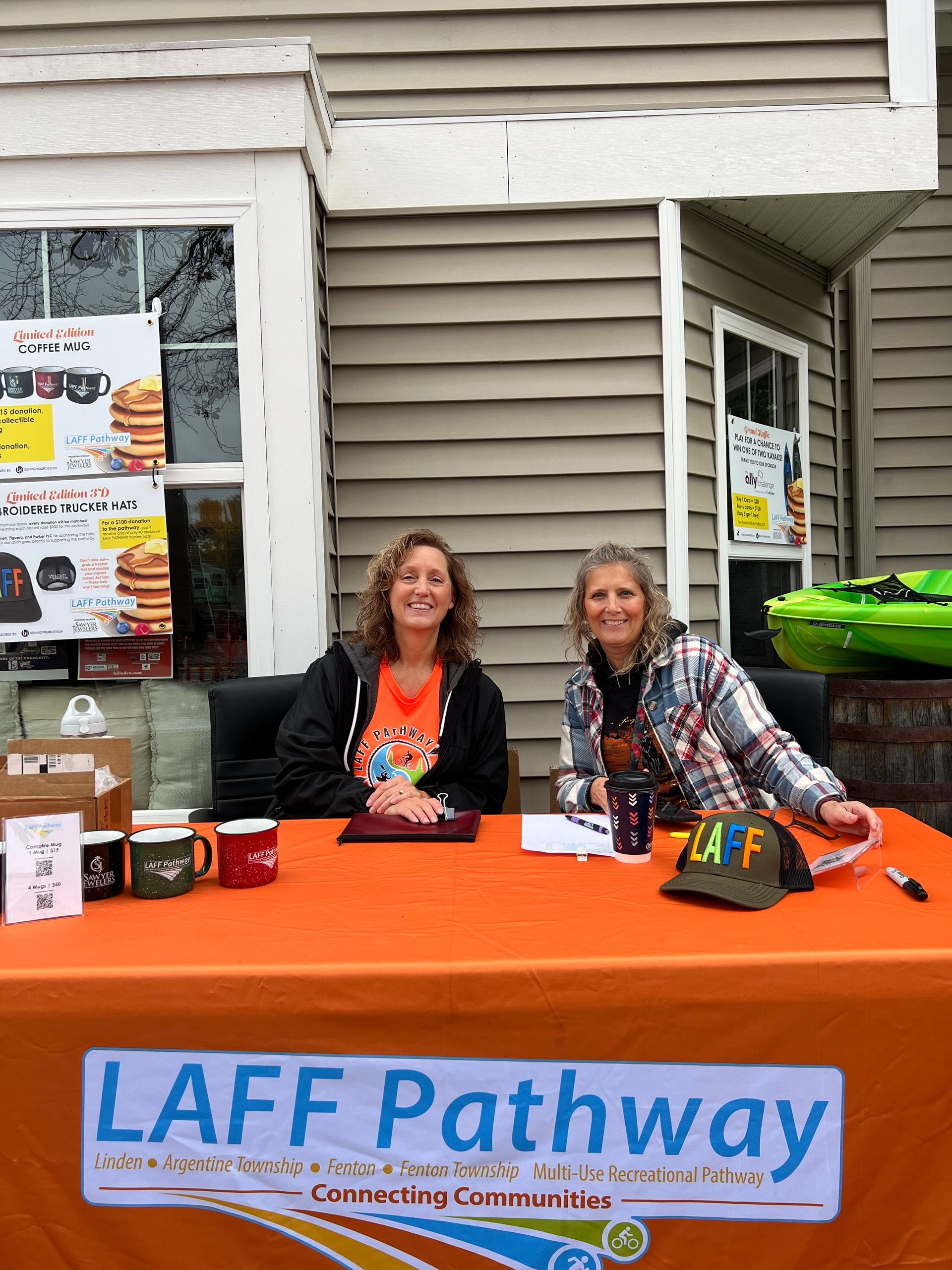 Two women are sitting at a table with a sign that says laff pathway.