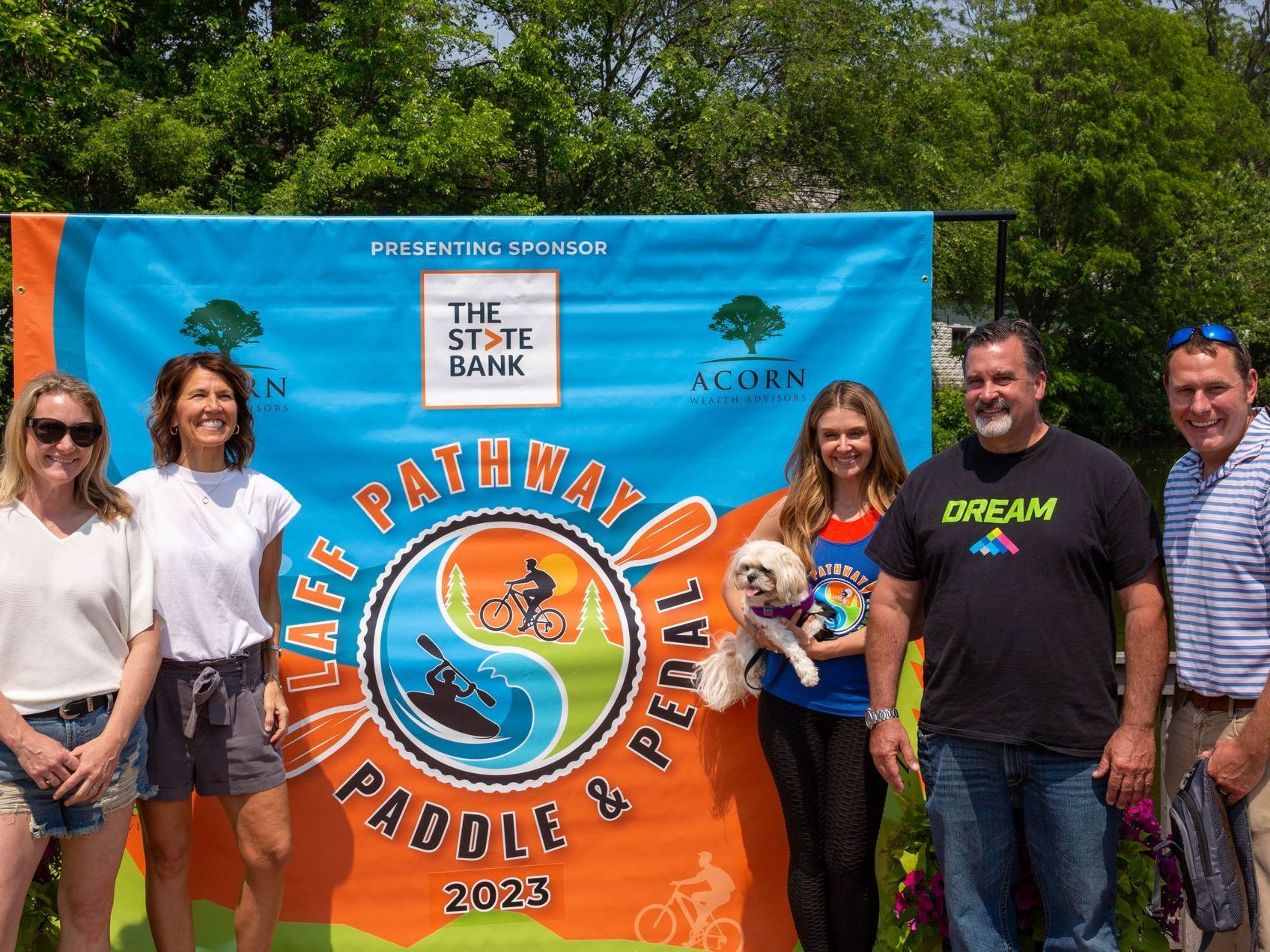 A group of people standing in front of a sign that says paddle and pedal
