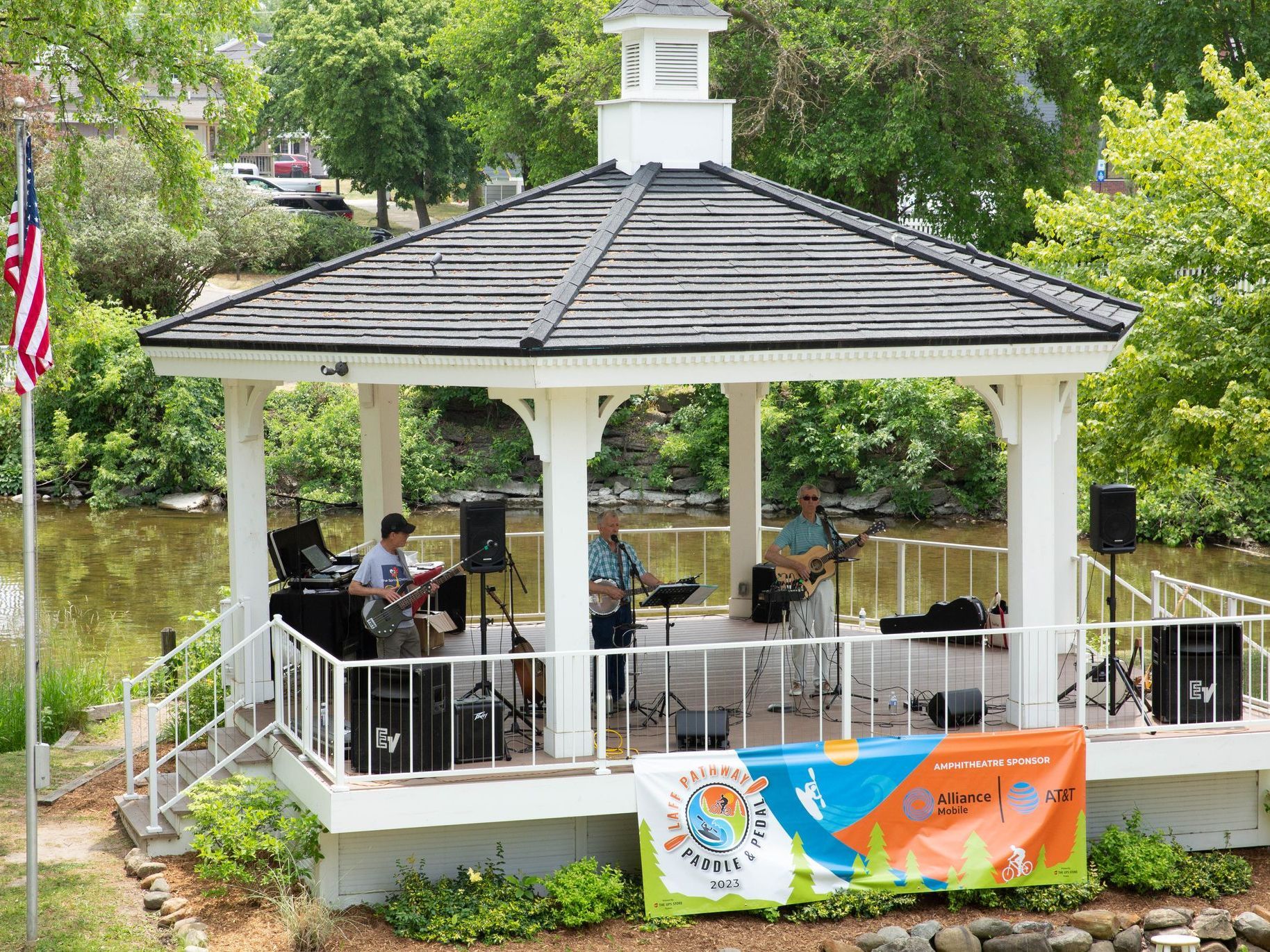 A band is playing music under a gazebo in a park.