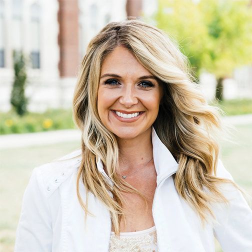 A woman in a white jacket is smiling for the camera.