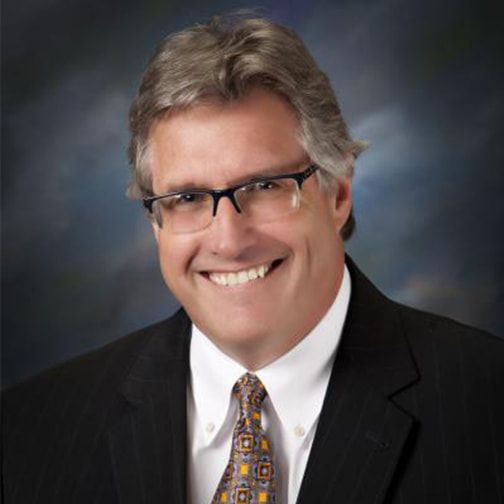 A man in a suit and tie is smiling for the camera.