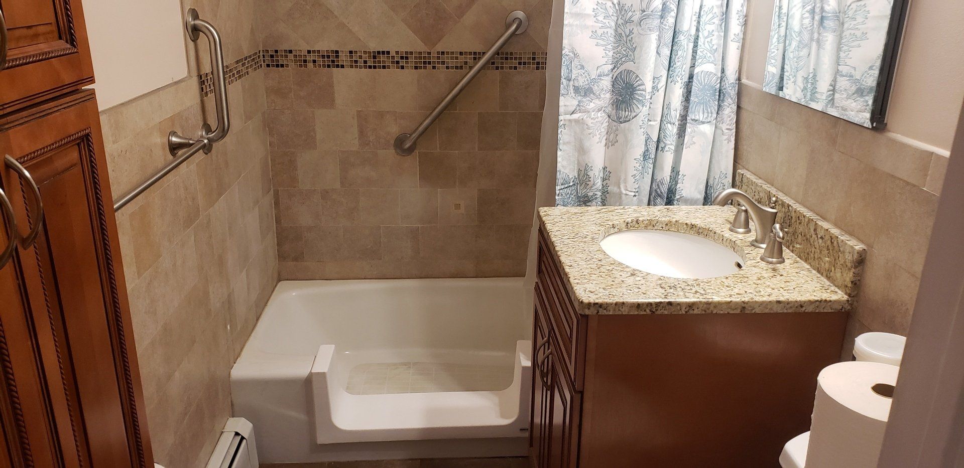 Bathroom with a step-in tub, beige tile walls, granite sink vanity, and curtained window