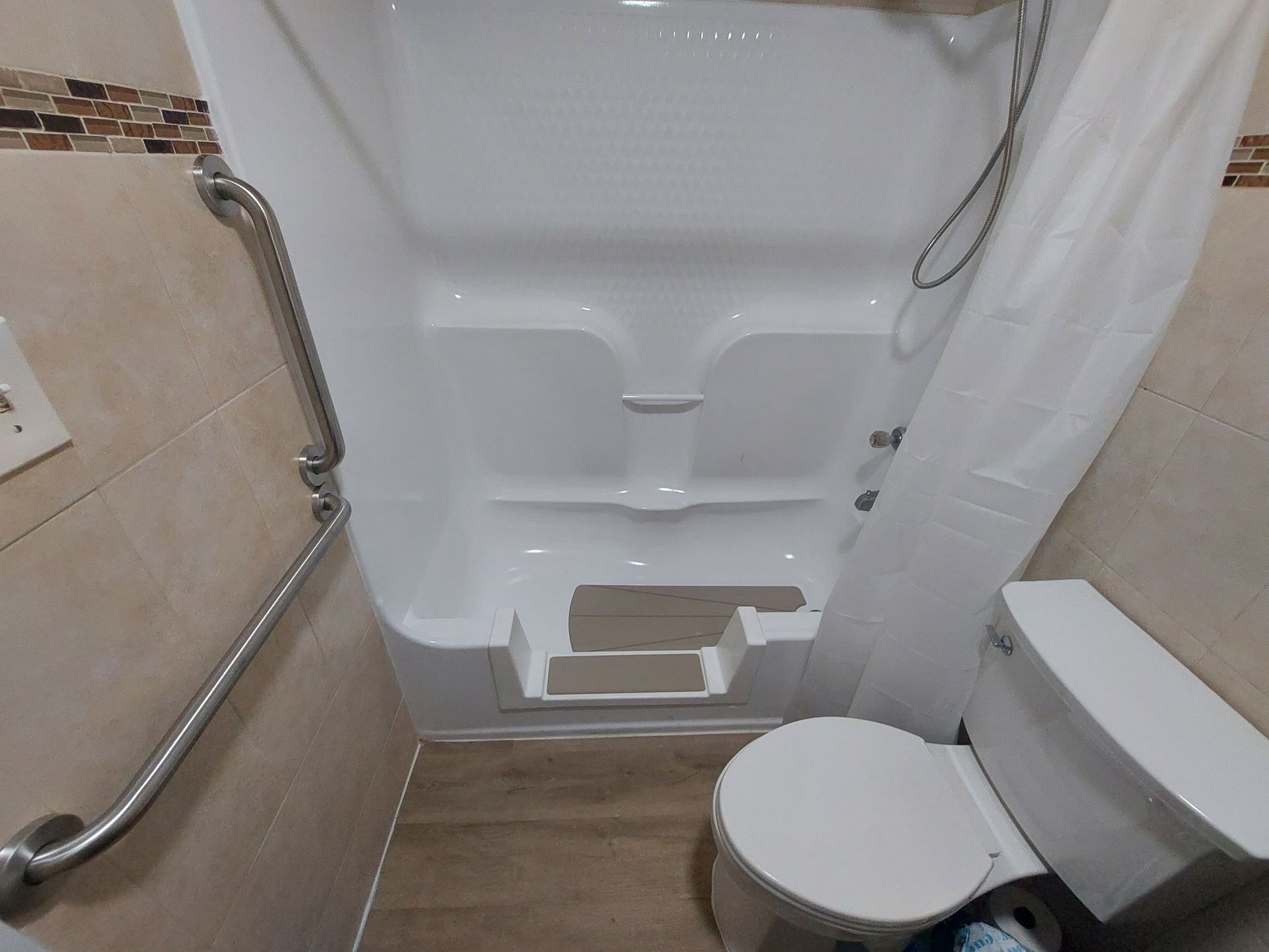 Accessible step-in shower and toilet with grab bars in a small bathroom