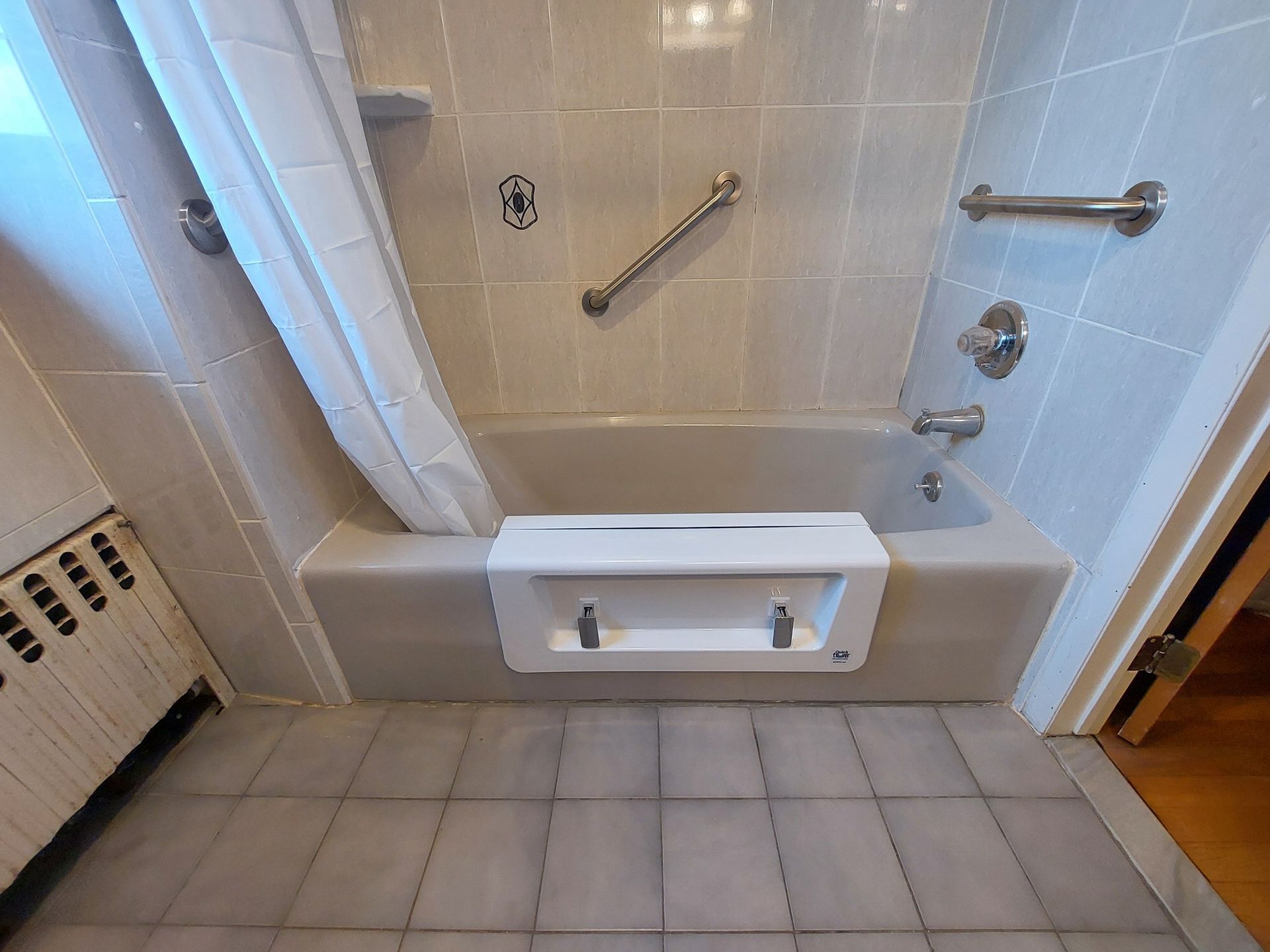 Accessible shower with grab bars, built-in seat, and tiled walls in a small bathroom.
