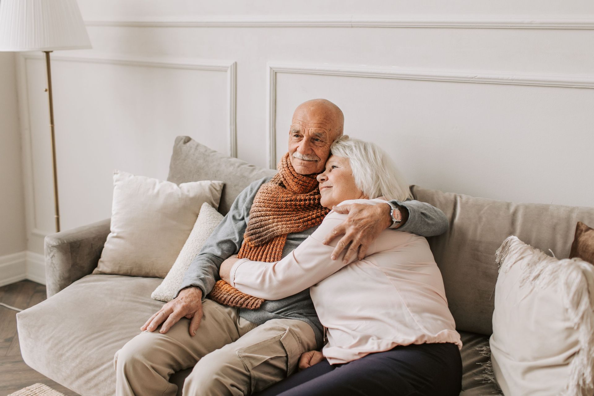Two people sitting on a couch, hugging in a bright living room