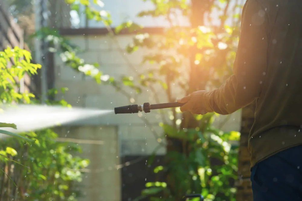 A Man is Using a High Pressure Washer to Clean the Outside of His House — Doobies Cleaning Service in Port Macquarie, NSW