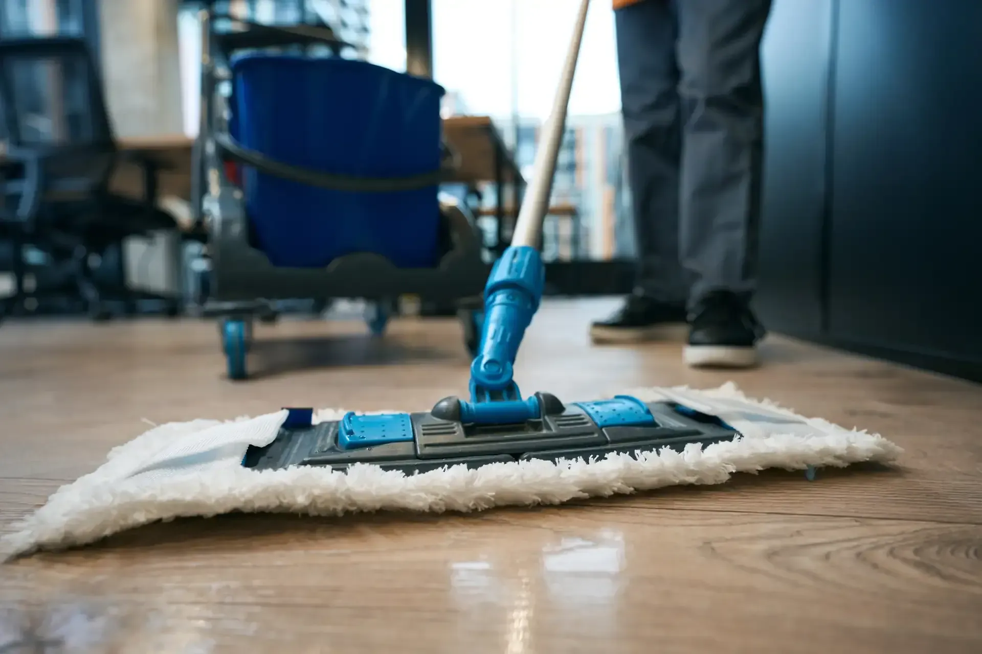 A Person is Cleaning a Wooden Floor With a Mop — Doobies Cleaning Service in Port Macquarie, NSW