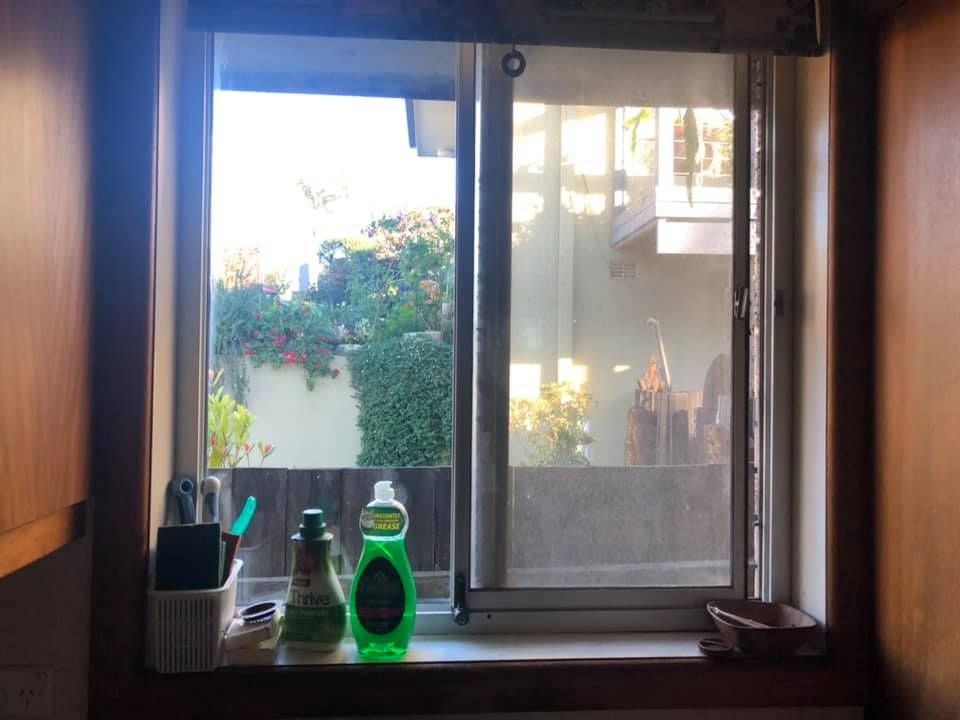 A Window With a Bottle of Dish Soap on the Window Sill — Doobies Cleaning Service in Port Macquarie, NSW