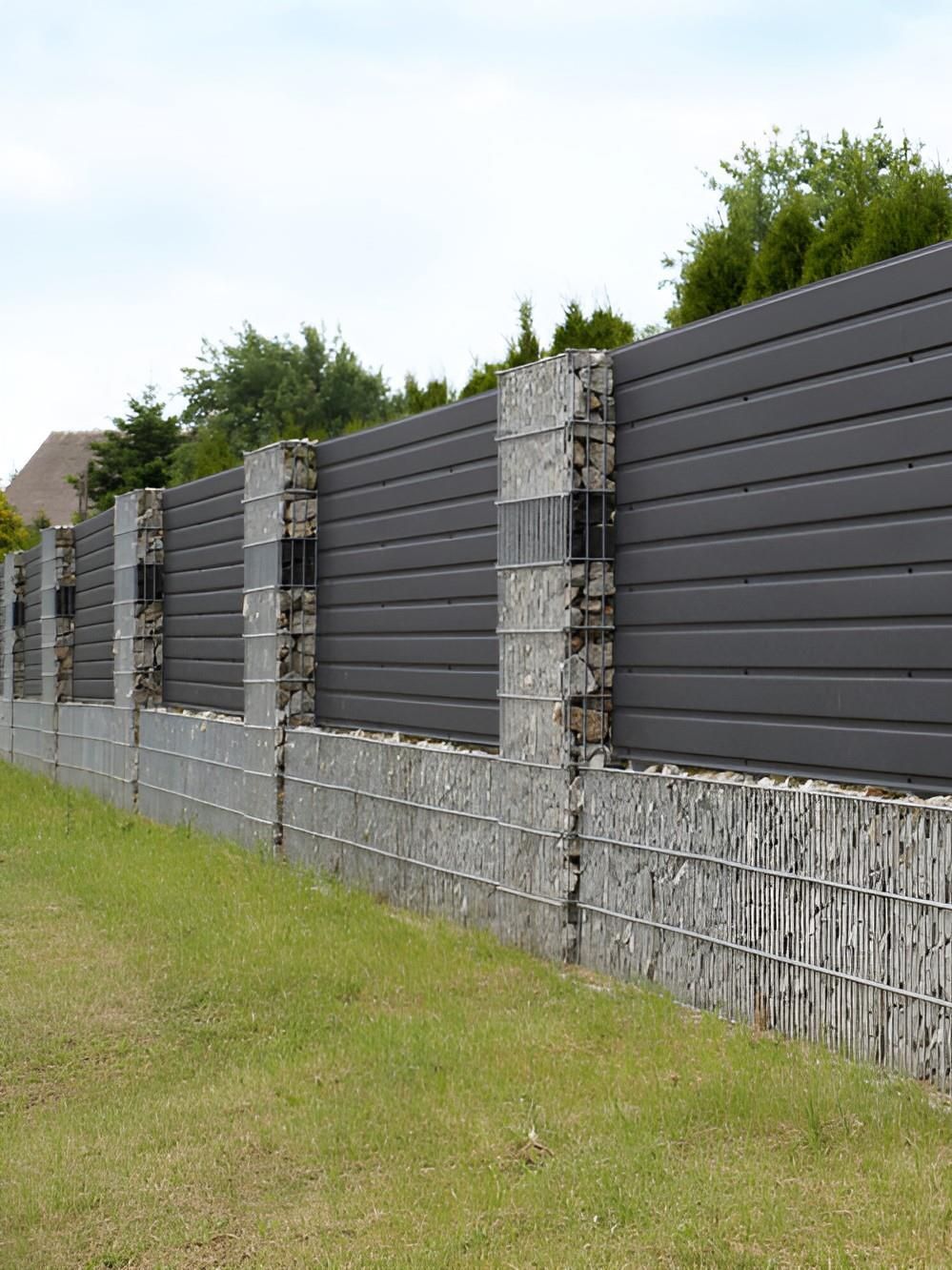 A Wall Made Of Wood And Rocks Is Surrounding A Grassy Field — GEO – AM Consulting In Lismore, NSW
