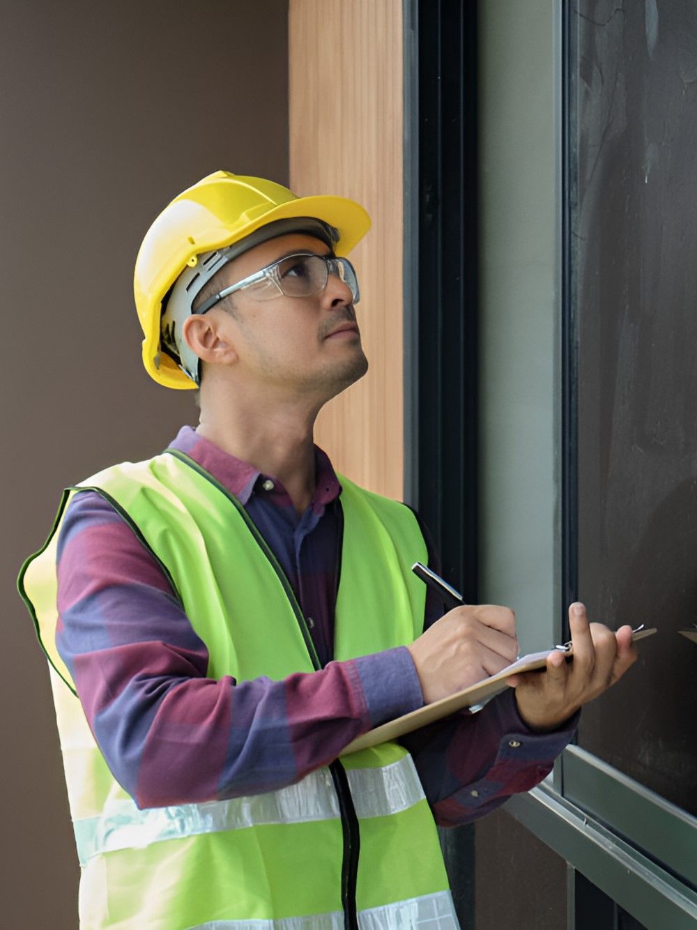 A Man Wearing A Hard Hat And Safety Vest Is Writing On A Clipboard — GEO – AM Consulting In Lismore, NSW