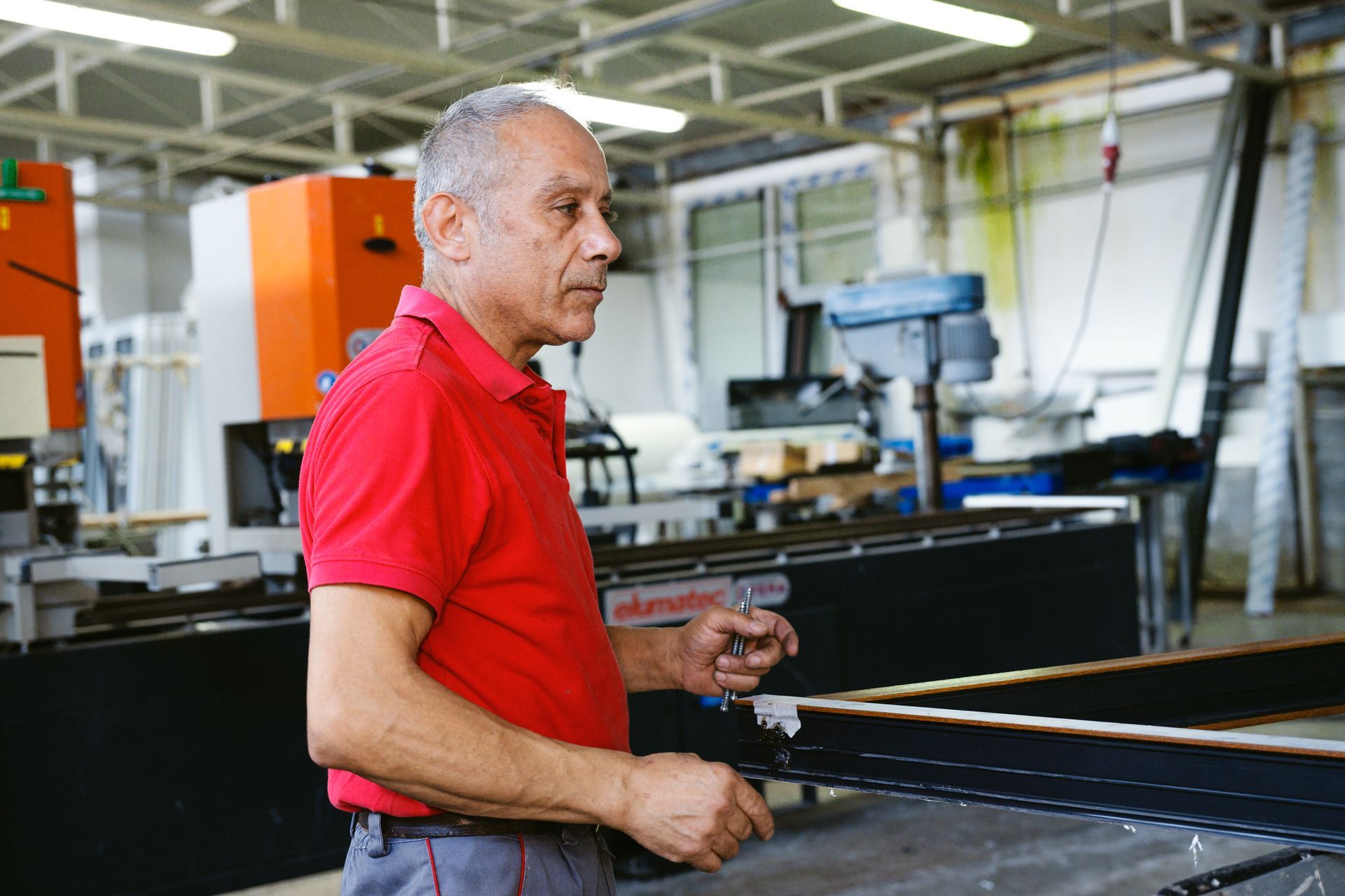 Un uomo con una camicia rossa sta lavorando in una fabbrica.