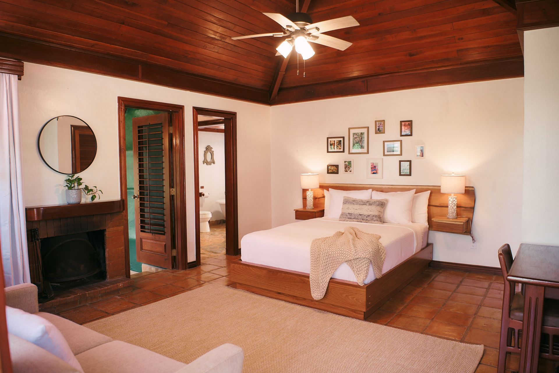 a bedroom with a bed , couch , fireplace and ceiling fan .