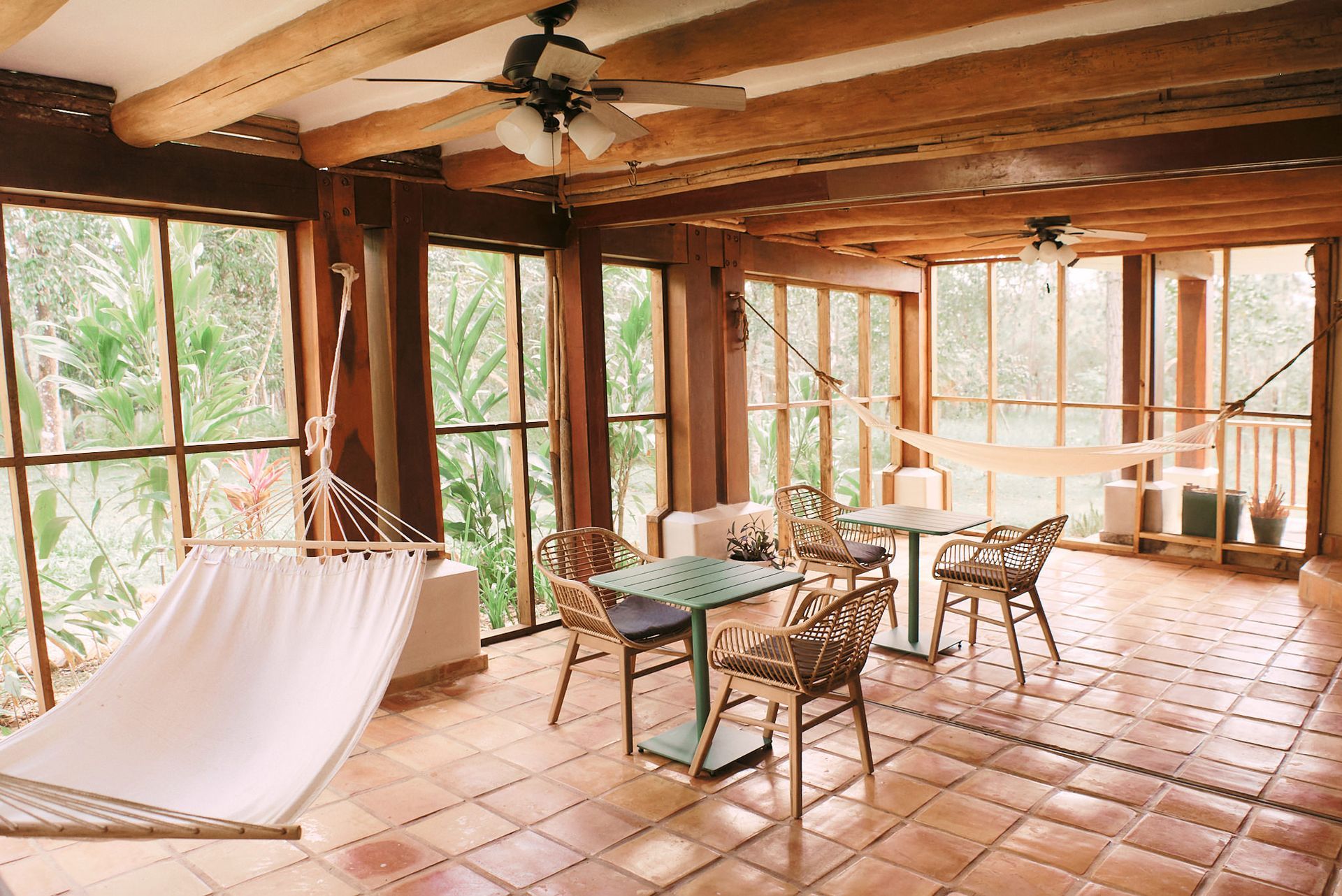 there is a hammock in the middle of the room with tables and chairs .