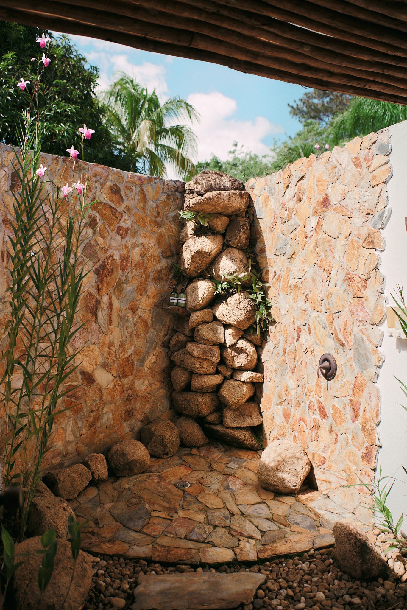A stone shower with a waterfall coming out of it.