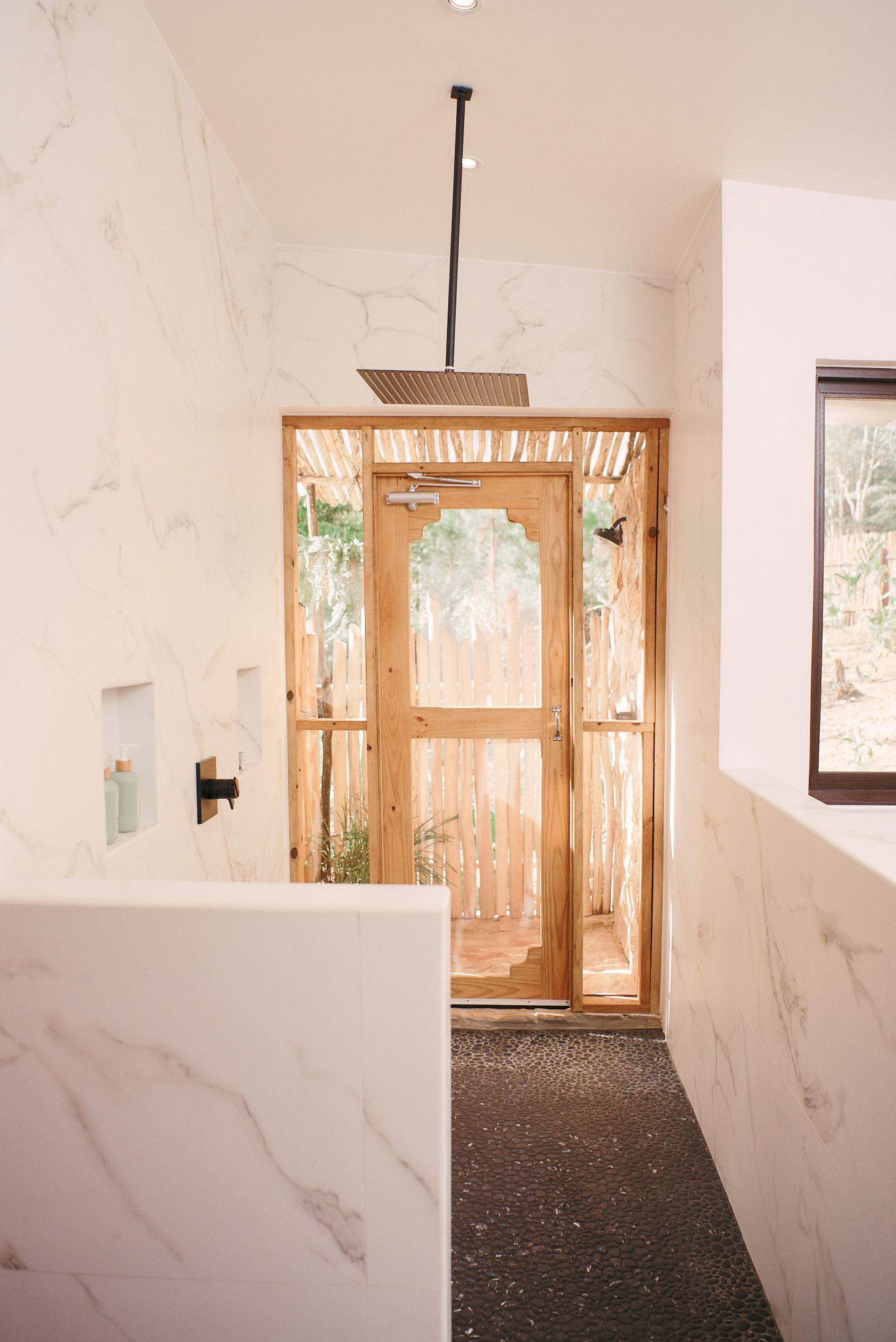 A bathroom with a walk in shower and a wooden door.