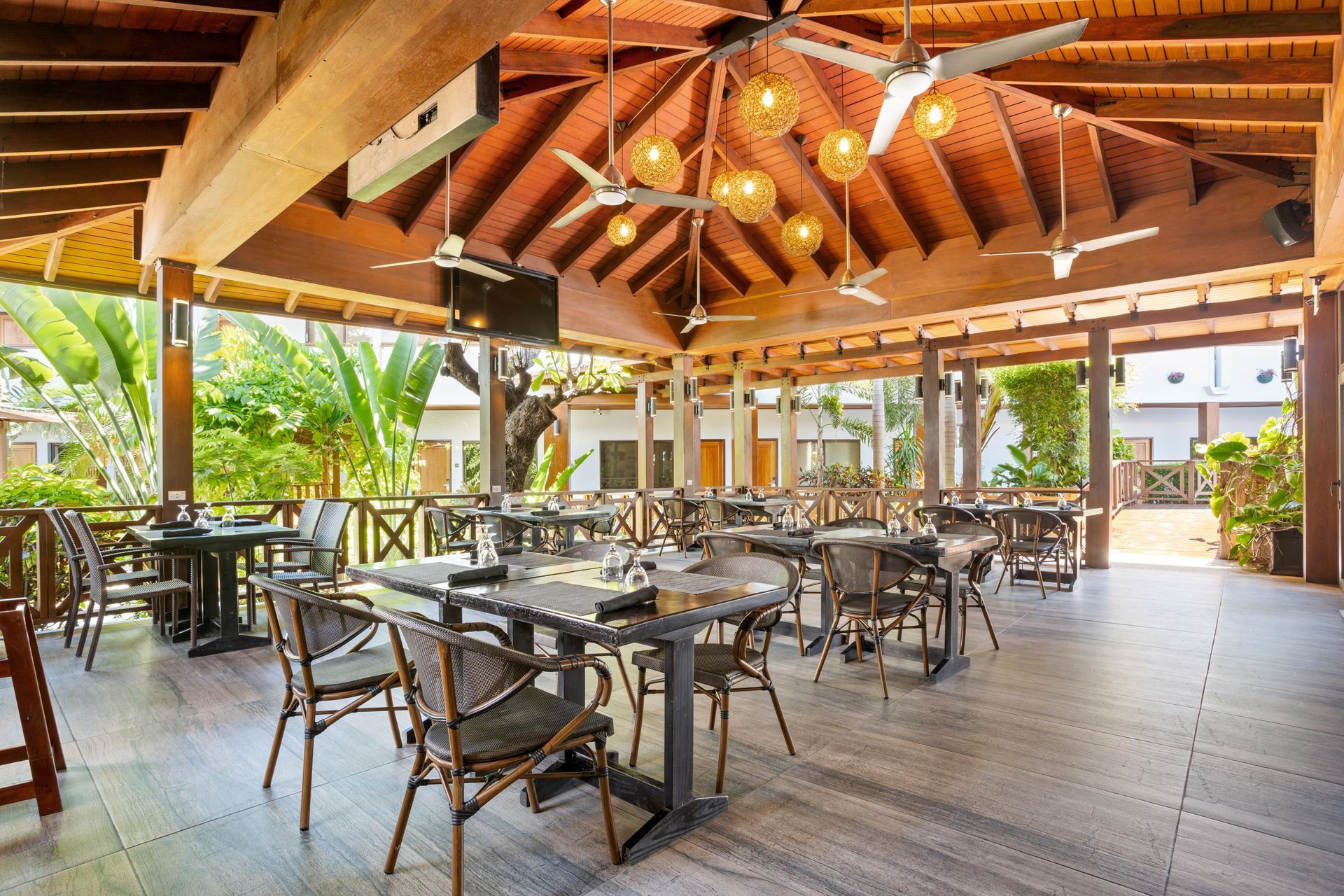 A restaurant with tables and chairs under a canopy with ceiling fans.