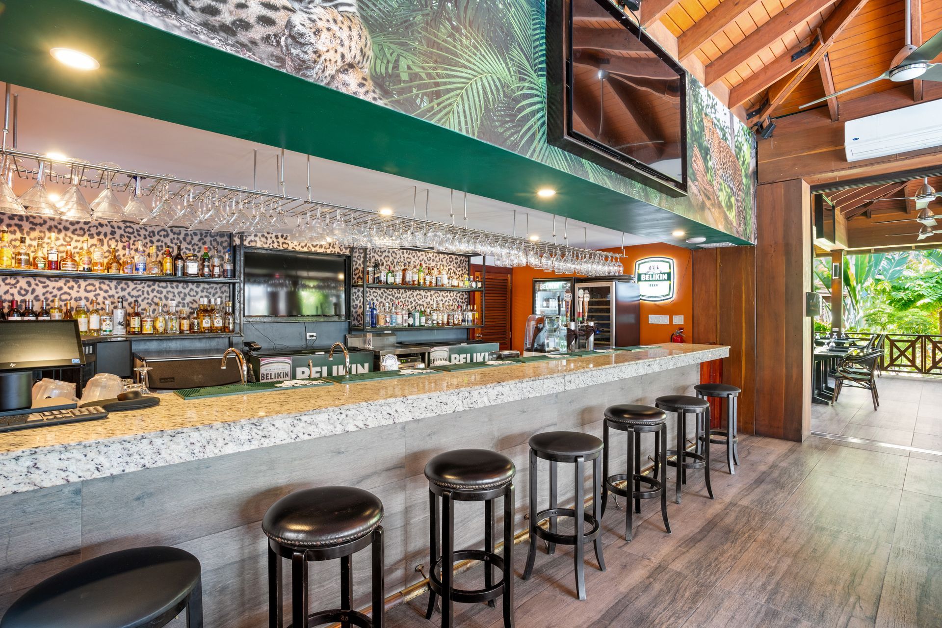 A long bar with stools and a television on the wall.