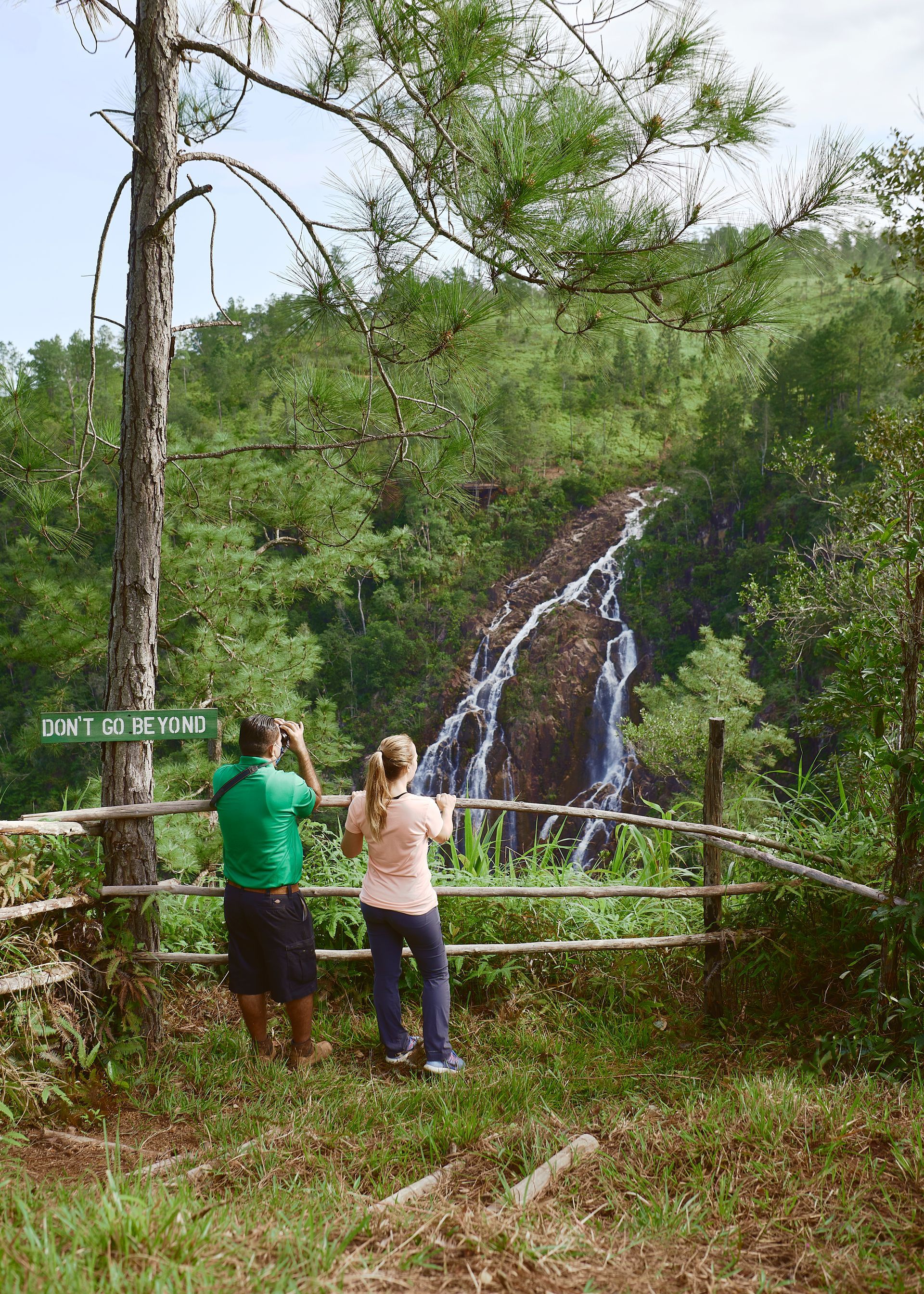 a man and a woman are standing in front of a waterfall .